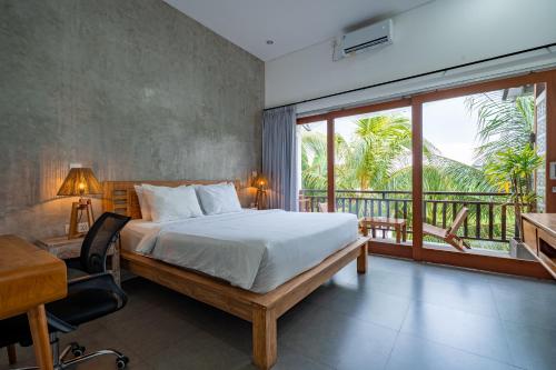 a bedroom with a bed and a desk and a window at Suksma Guesthouse in Canggu