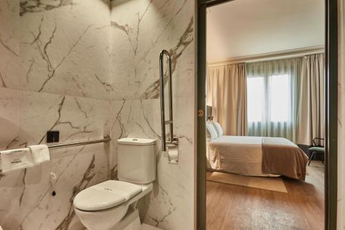 a bathroom with a toilet and a bed at Silken Gran hotel Durango in Durango
