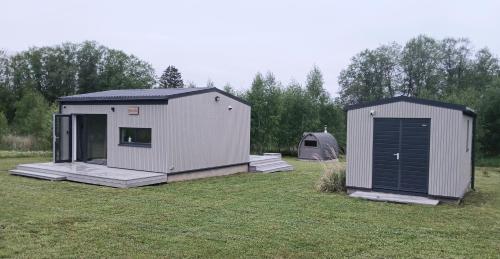 two small buildings in a field with a tent at Elenos sodyba in Puorai