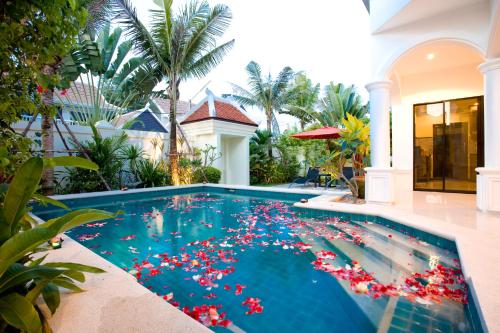 a swimming pool with red flowers in the water at Palm Grove Resort, Pattaya in Na Jomtien