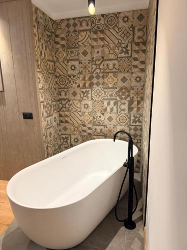 a white bath tub in a bathroom with a tile wall at Albergo Maggiorina in Ledro