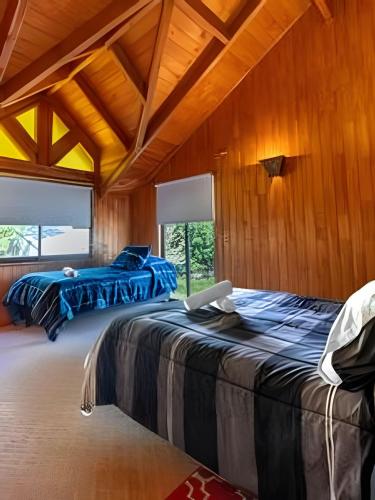 zwei Betten in einem Zimmer mit Holzwänden in der Unterkunft Impresionante casa + Starlink | Bosque y estufa in Pucón