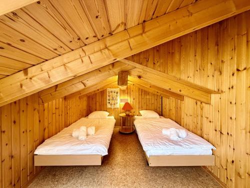 two beds in a room with wooden walls at Eanta SUNNY & MOUNTAIN chalet 10 pers by Alpvision Résidences in Veysonnaz