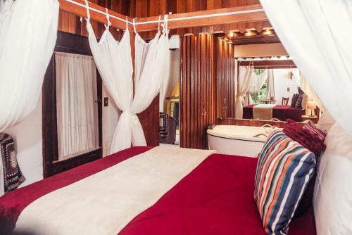 a bedroom with a bed and a tub in a room at Chalés Recanto da cachoeira in Monte Verde
