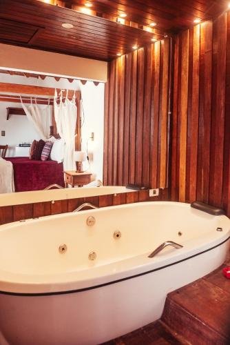 a bath tub in a room with a bedroom at Chalés Recanto da cachoeira in Monte Verde