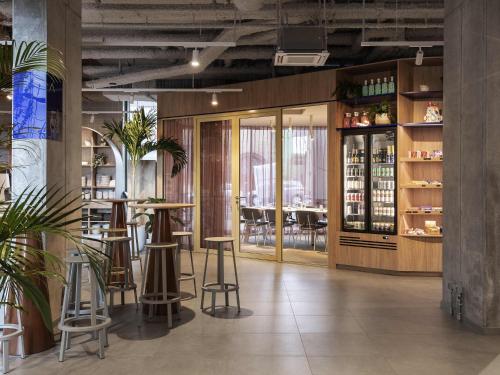 a bar in a restaurant with stools and tables at Adagio Access Gent Centrum Dampoort in Ghent