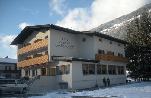 a building with people standing outside of it in the snow at Gasthof Sprenger in Sillian