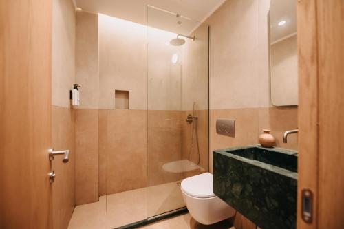 a bathroom with a toilet and a glass shower at Hotel Apollon Corfu in Paleokastritsa