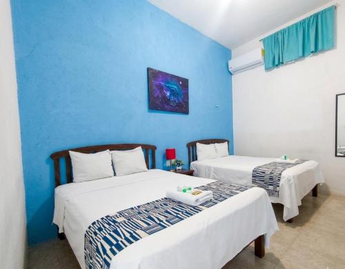 zwei Betten in einem Zimmer mit blauen Wänden in der Unterkunft Balamku Hotel Petit in Campeche