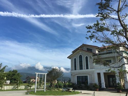 a white house with a blue sky and mountains at Sweetlight B&B in Jiaoxi