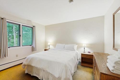 a white bedroom with a large bed and two windows at Seasons 207 in Warren