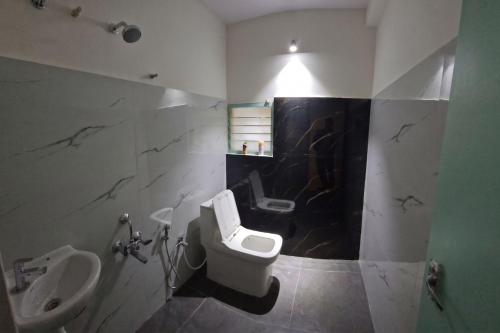 a bathroom with a toilet and a urinal and a sink at Kattil Chennai in Chennai