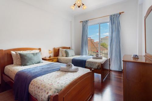 a bedroom with two beds and a window at Paradise Dream in Caniço