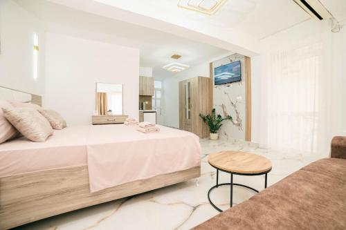 a white bedroom with a large bed and a table at Villa Champion in Ulcinj