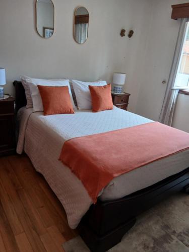 a bedroom with a large bed with orange and white pillows at Casa Rural in Esposende