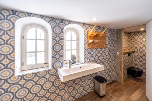 a bathroom with a sink and two windows at Casa da Figueira in Ericeira