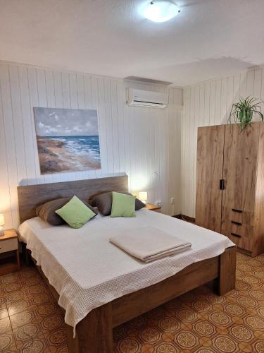 a bedroom with a large bed with two green pillows at Apartmani Emi in Tučepi