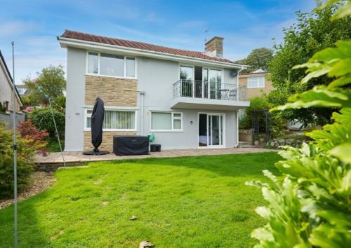 a house with a green lawn in front of it at Sea Gem - large holiday cottage in Tenby with private parking in Tenby