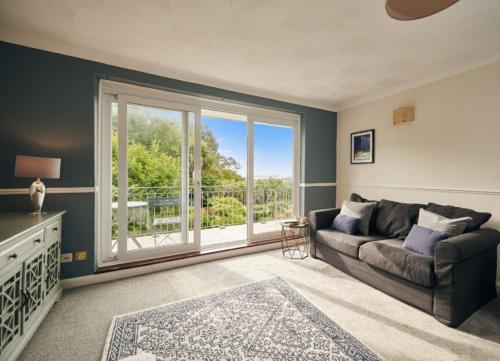 a living room with a couch and a large window at Sea Gem - large holiday cottage in Tenby with private parking in Tenby