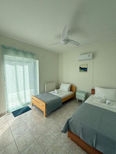 a bedroom with two beds and a ceiling fan at Green House Schinias in Káto Soúlion