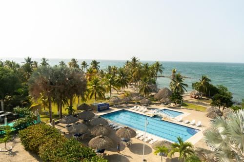 a view of a pool with umbrellas and the ocean at Coveñas - Condominio Puntepiedra Hotel in Coveñas