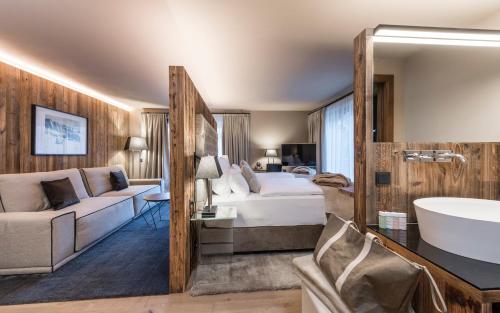 een hotelkamer met een bed, een wastafel en een bad bij Hotel Montchalet in Ortisei