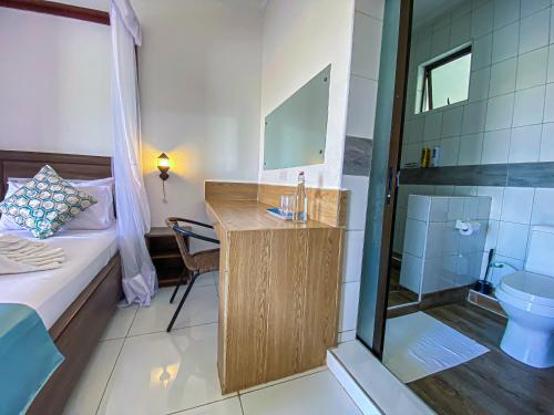 a small bathroom with a sink and a shower at The Safiya Hotel, Diani Beach, "Formely Diani Palm Resort" in Diani Beach