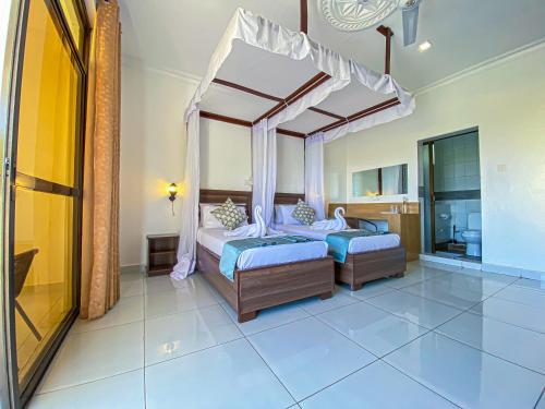 a bedroom with two beds and a canopy bed at The Safiya Hotel, Diani Beach, "Formely Diani Palm Resort" in Diani Beach