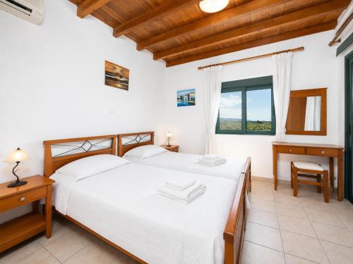 a bedroom with a bed and a desk and a window at Andreas Beach Villa in Sfakia