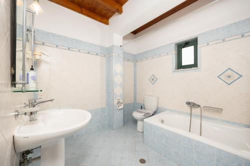 a bathroom with a sink and a tub and a toilet at Andreas Beach Villa in Sfakia