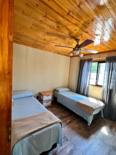 a bedroom with two beds and a ceiling fan at Cabañas Los Robles Premium in Villa Quillinzo
