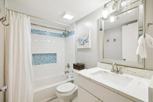 a white bathroom with a tub and a sink and a toilet at Emerald Hideaway by 30A Escapes in Carillon Beach