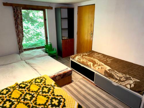 a bedroom with two beds and a window at Chata Lesní Vyhlídka in Splzov