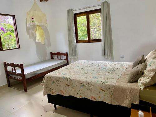 a bedroom with a bed and a bench and windows at Casa Lilás no Vale do Capão in Vale do Capao