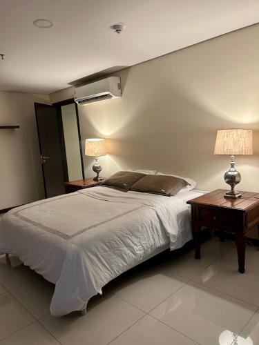 a bedroom with a bed with two tables and two lamps at Viel Comfort II in Asunción