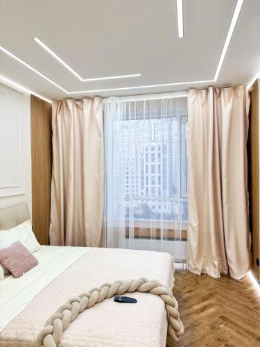 a bedroom with a bed and a large window at DailyRentKZ in Kostanay