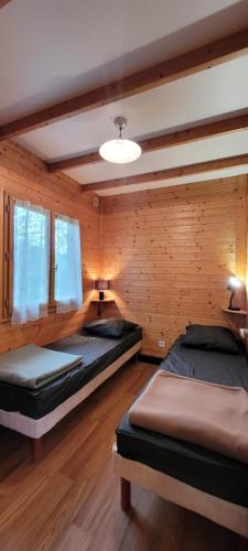 a bedroom with two beds in a wooden room at Camping de Saint Just - Onlycamp in Arcomie