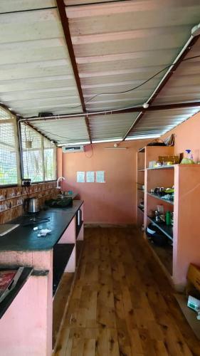 a large kitchen with a wooden floor and pink walls at Rootscape Huts Hostel and Home Stay in Auroville