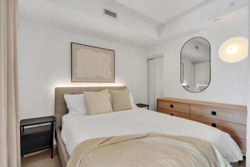 a bedroom with a white bed and a mirror at Work-Friendly 1BR Suite Steps to Eaton Centre in Toronto