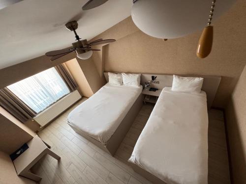 a small room with two beds and a ceiling fan at Hotel Cinas in Eskisehir