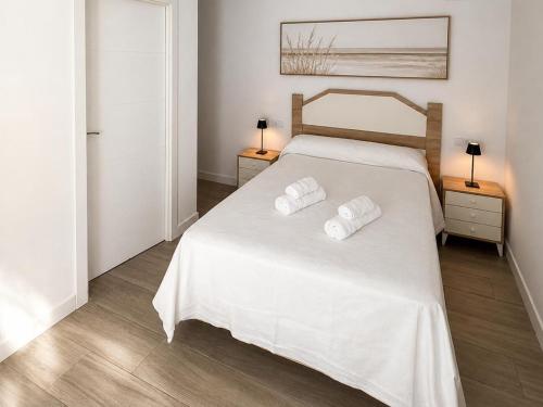 a bedroom with a white bed with two towels on it at Hospedium GL Linarejos Suites Parking Gratis in Linares