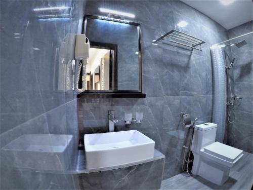 a bathroom with a sink and a toilet and a mirror at Seaside Villa in Dhiffushi