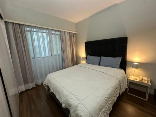 a bedroom with a large bed and a large window at Hotel & Residence Alphaville in Barueri