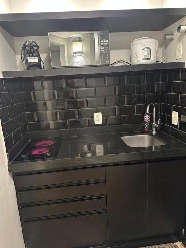 a kitchen counter with a sink and a microwave at Hotel & Residence Alphaville in Barueri