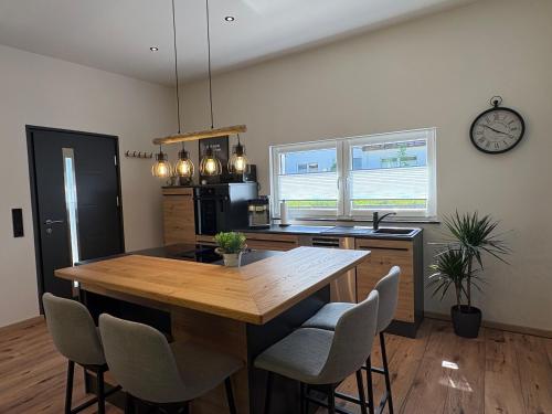 a kitchen with a wooden table and chairs and a clock at Ferienhaus Lenz in Kalenborn