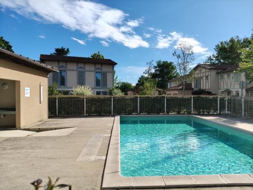 a swimming pool in a yard next to a fence at La gemmeuse Meublé de tourisme 3 étoiles in Aureilhan