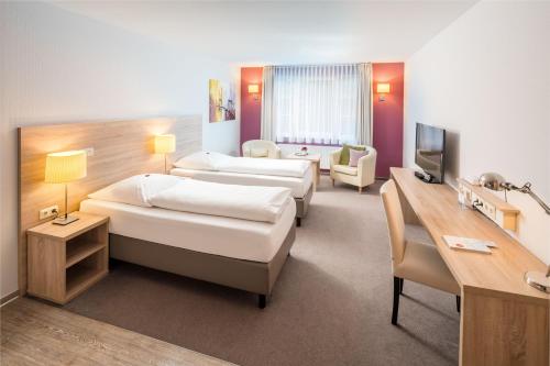 a hotel room with two beds and a desk at Hotel Westerfeld in Hemmingen