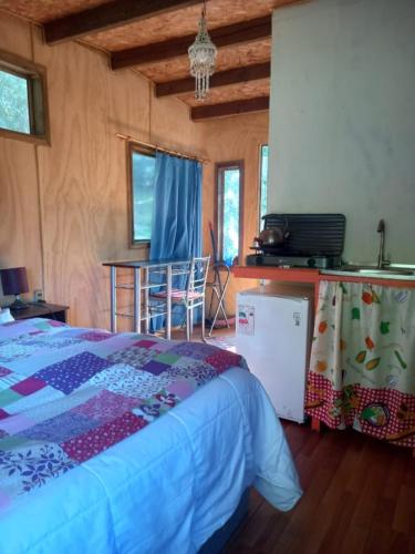 a bedroom with a bed and a table with a chair at Cabañita en la Isla in Isla Negra