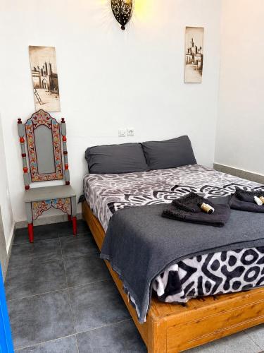 a bedroom with a bed and a chair and a mirror at Hôtel grand Atlas in Mirleft