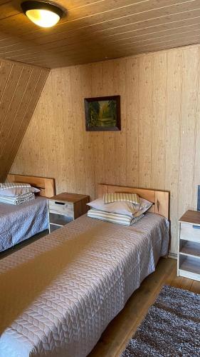 two beds in a room with wooden walls at Lauku sēta Svētupes in Salacgrīva